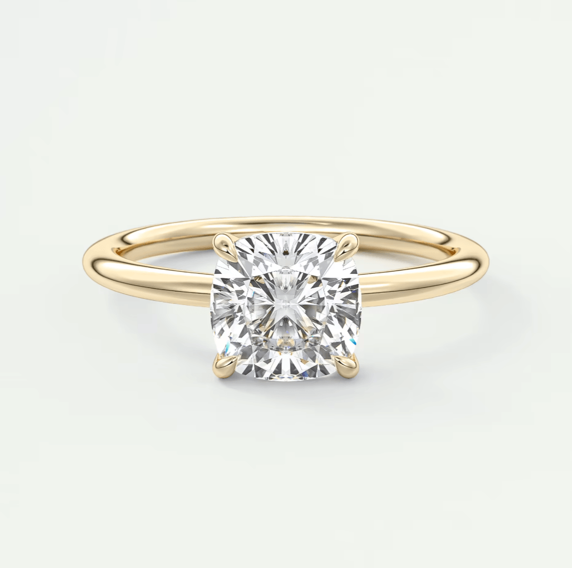 18-karat yellow gold solitaire diamond engagement ring with a cushion-cut center stone.