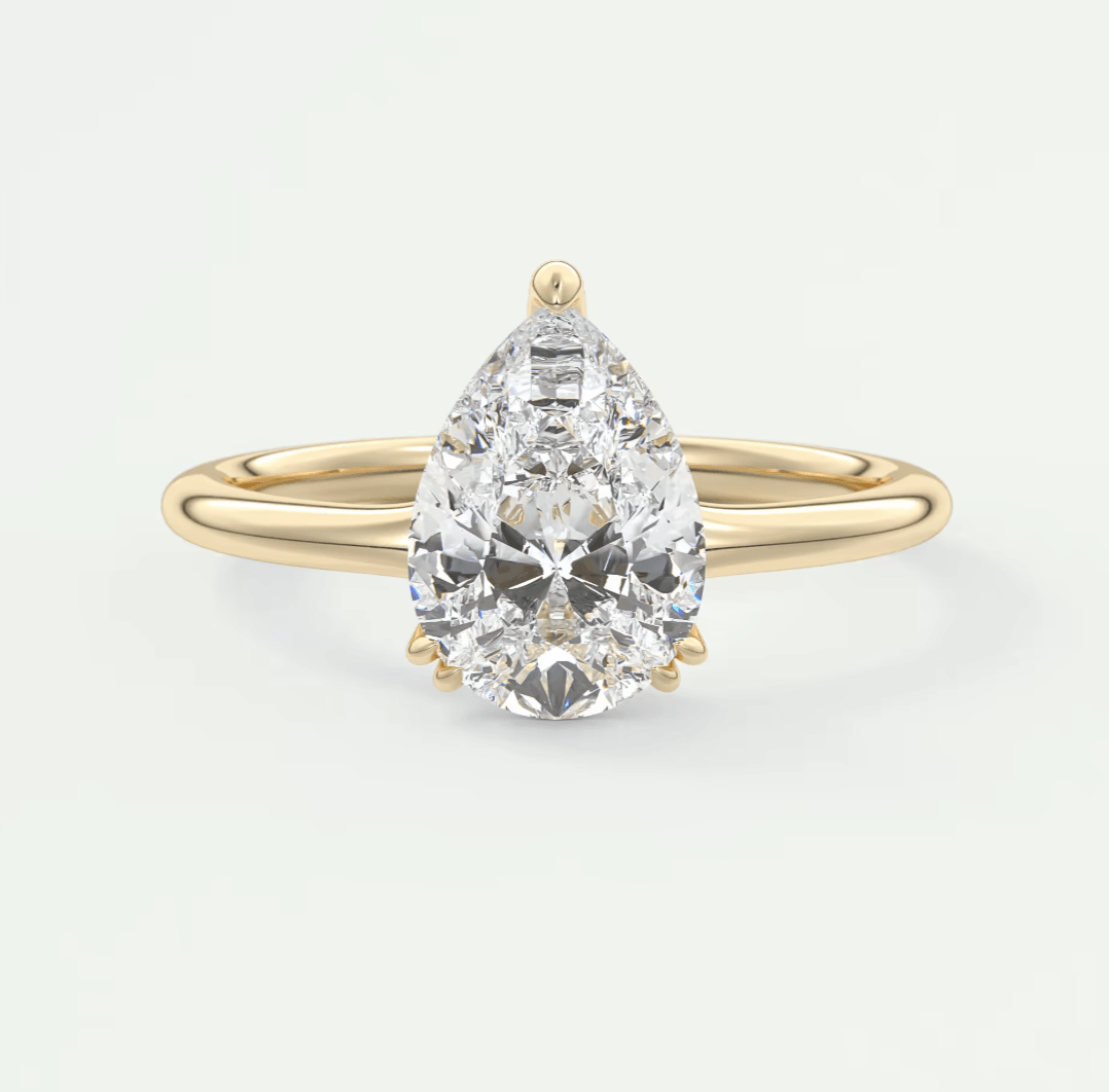Pear-shaped diamond engagement ring with gold band and prong setting.