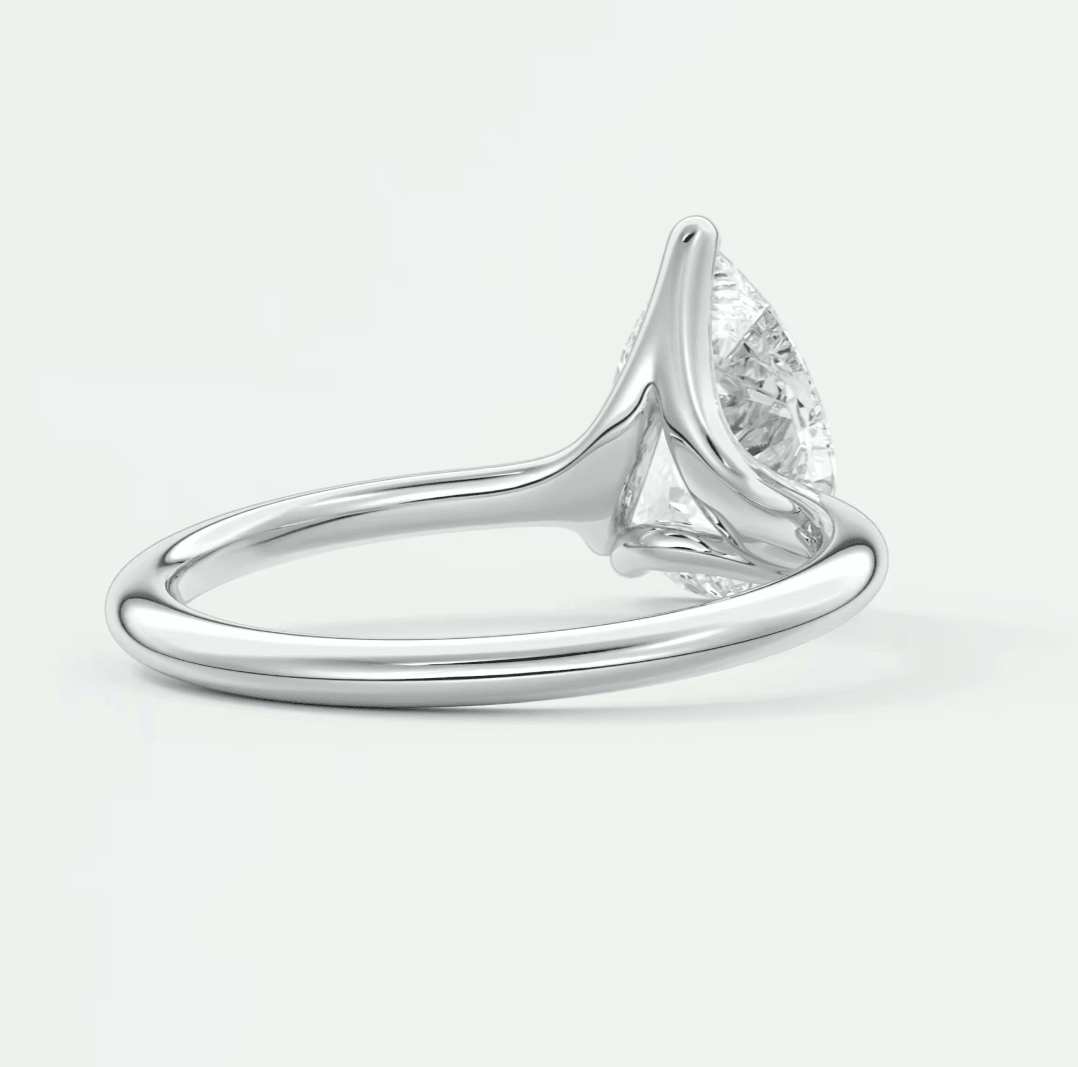 Silver diamond engagement ring with a pear-shaped stone and intricate band design.