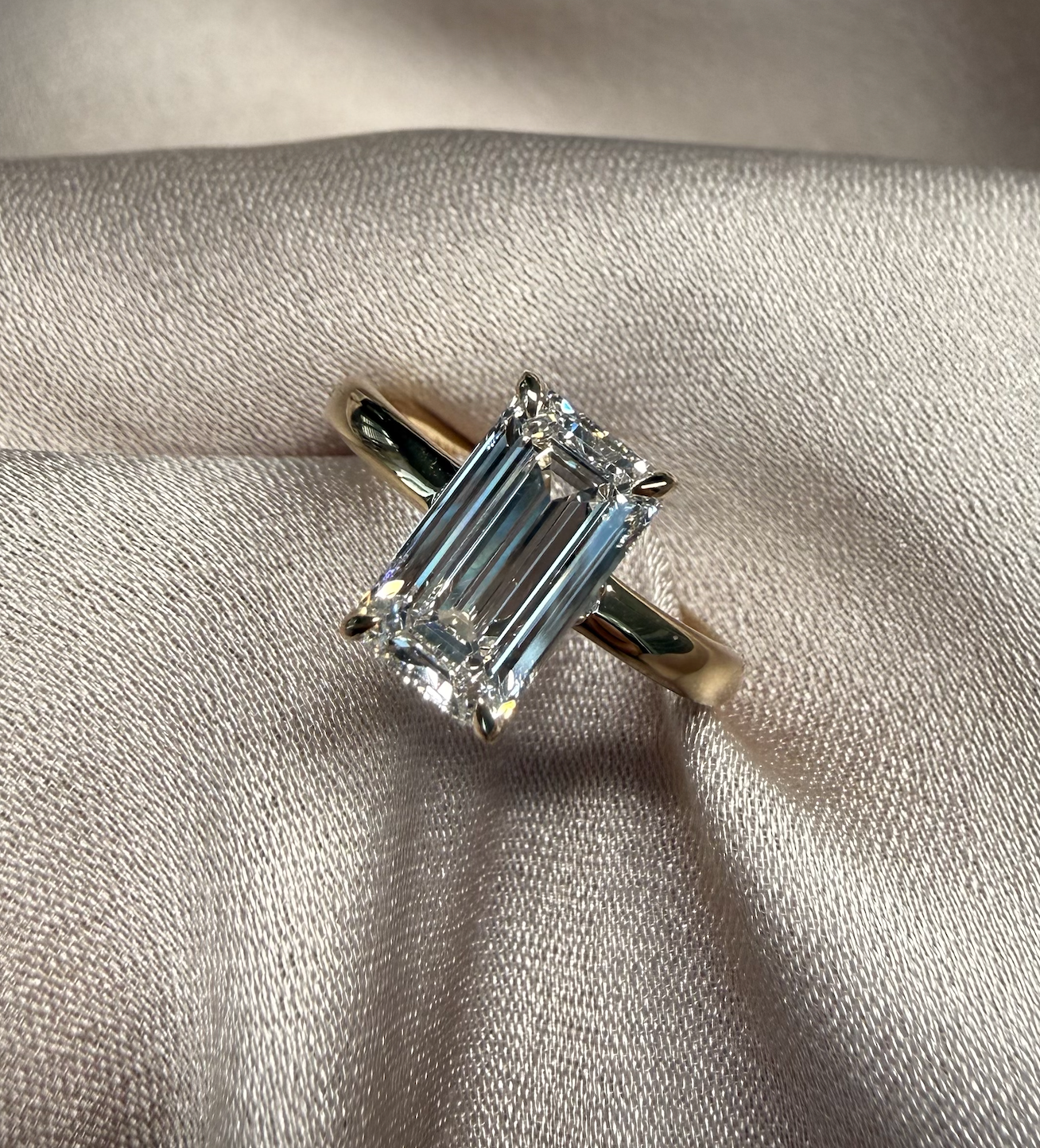 Diamond ring with emerald-cut center stone hidden halo