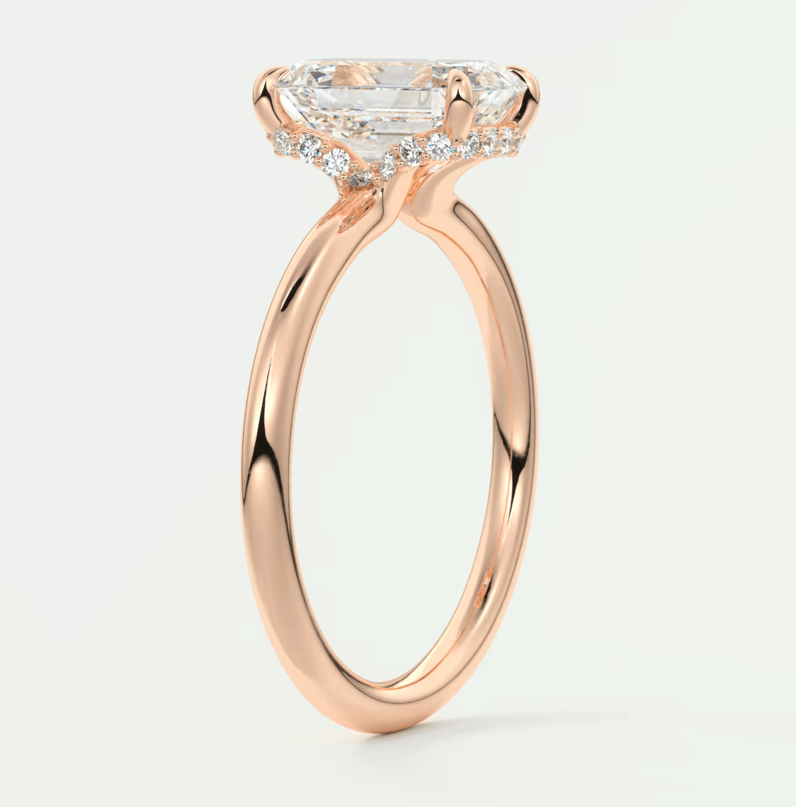 18-karat rose gold engagement ring with a princess-cut diamond and halo of smaller diamonds.
