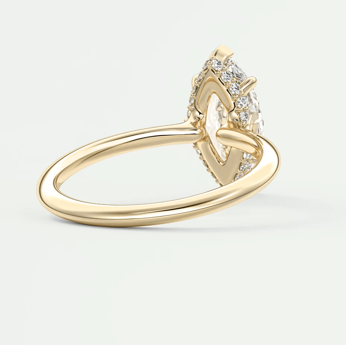 18k yellow gold engagement ring with a pear-shaped diamond and halo of smaller diamonds.