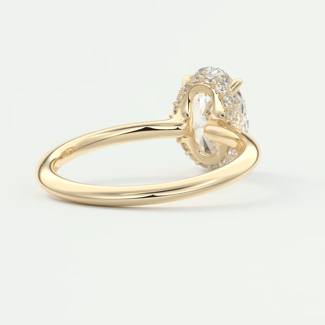 18k yellow gold engagement ring with a pear-shaped diamond and halo of smaller diamonds.
