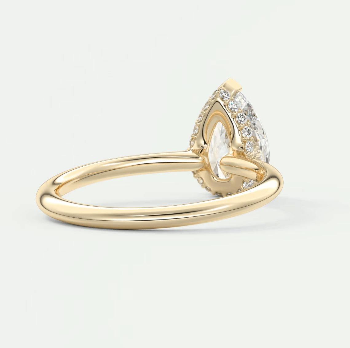 18k gold engagement ring with a pear-shaped diamond and halo of smaller diamonds.
