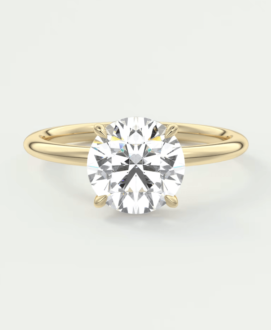 A round-cut diamond or moissanite stone set in a yellow gold band with a hidden halo underneath.