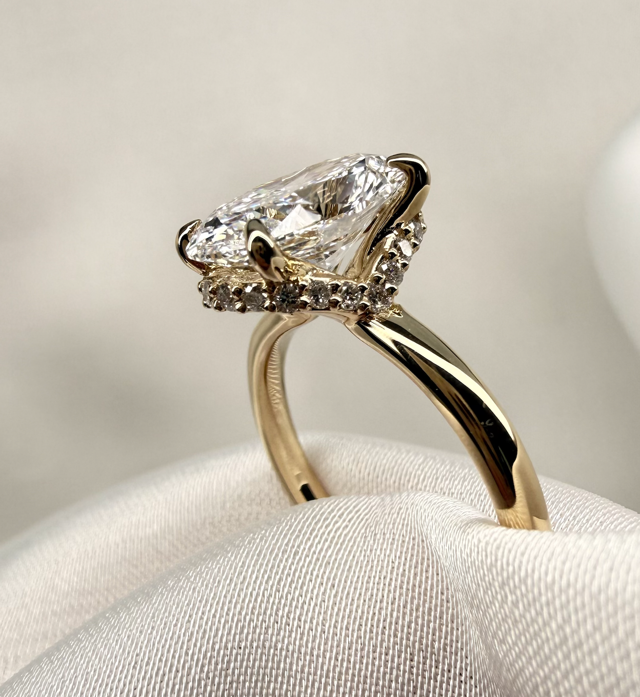 Gold ring with a large diamond on a white cushion