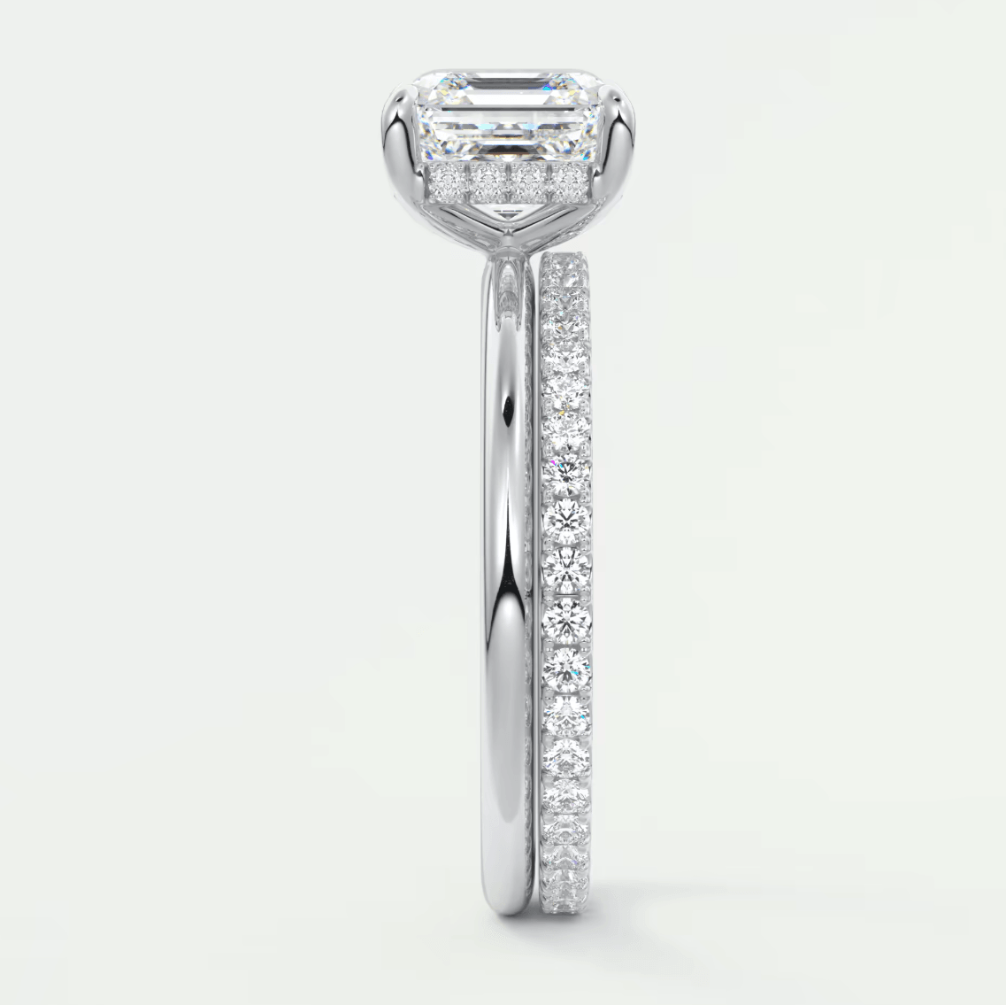 18k white gold diamond engagement ring with an emerald-cut center stone and pavé set diamonds on the band.