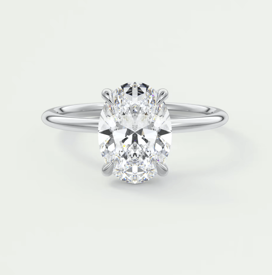 18-karat white gold oval diamond engagement ring with a princess cut center stone and baguette side stones.
