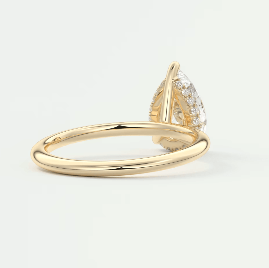 18k yellow gold pear-shaped diamond engagement ring with a halo of smaller diamonds.