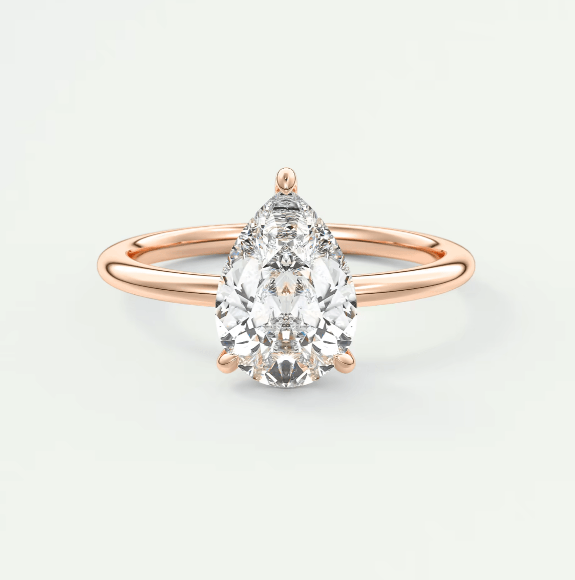 Rose gold pear-shaped diamond engagement ring with a solitaire setting.