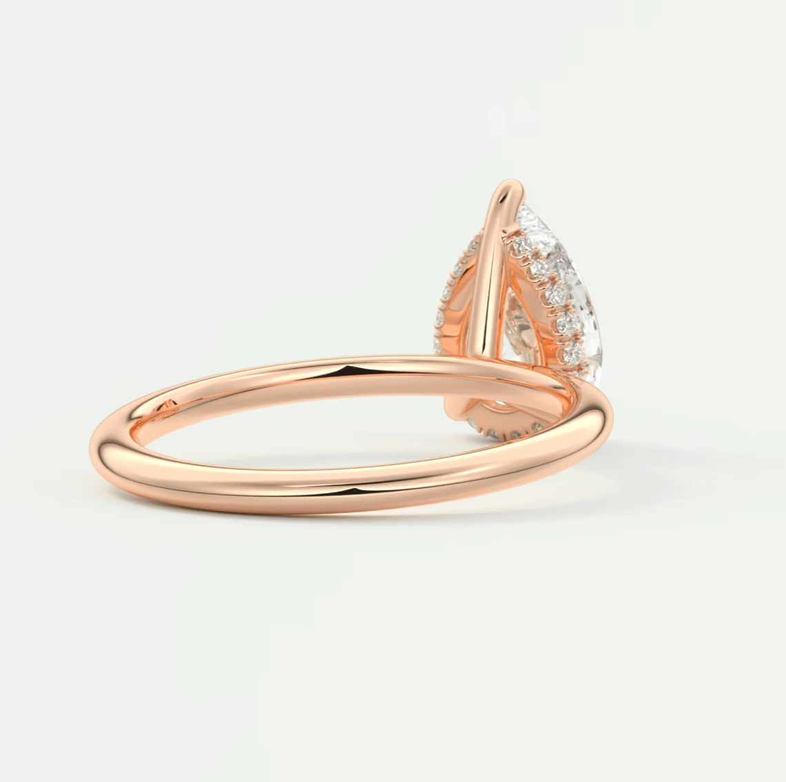 Rose gold pear-shaped diamond engagement ring with a halo of smaller diamonds.