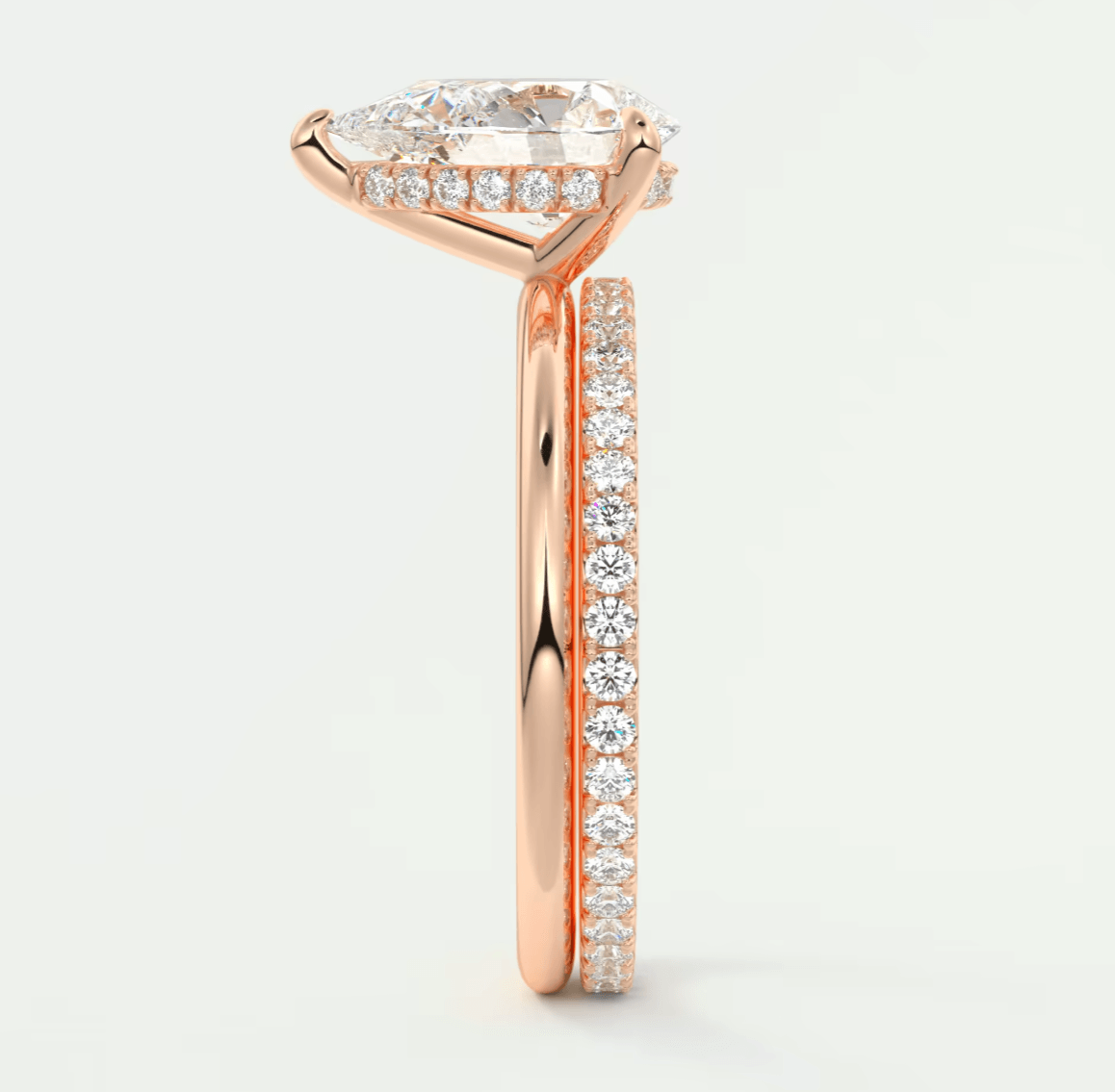 18k rose gold engagement ring with a pear-shaped diamond and pavé side stones.