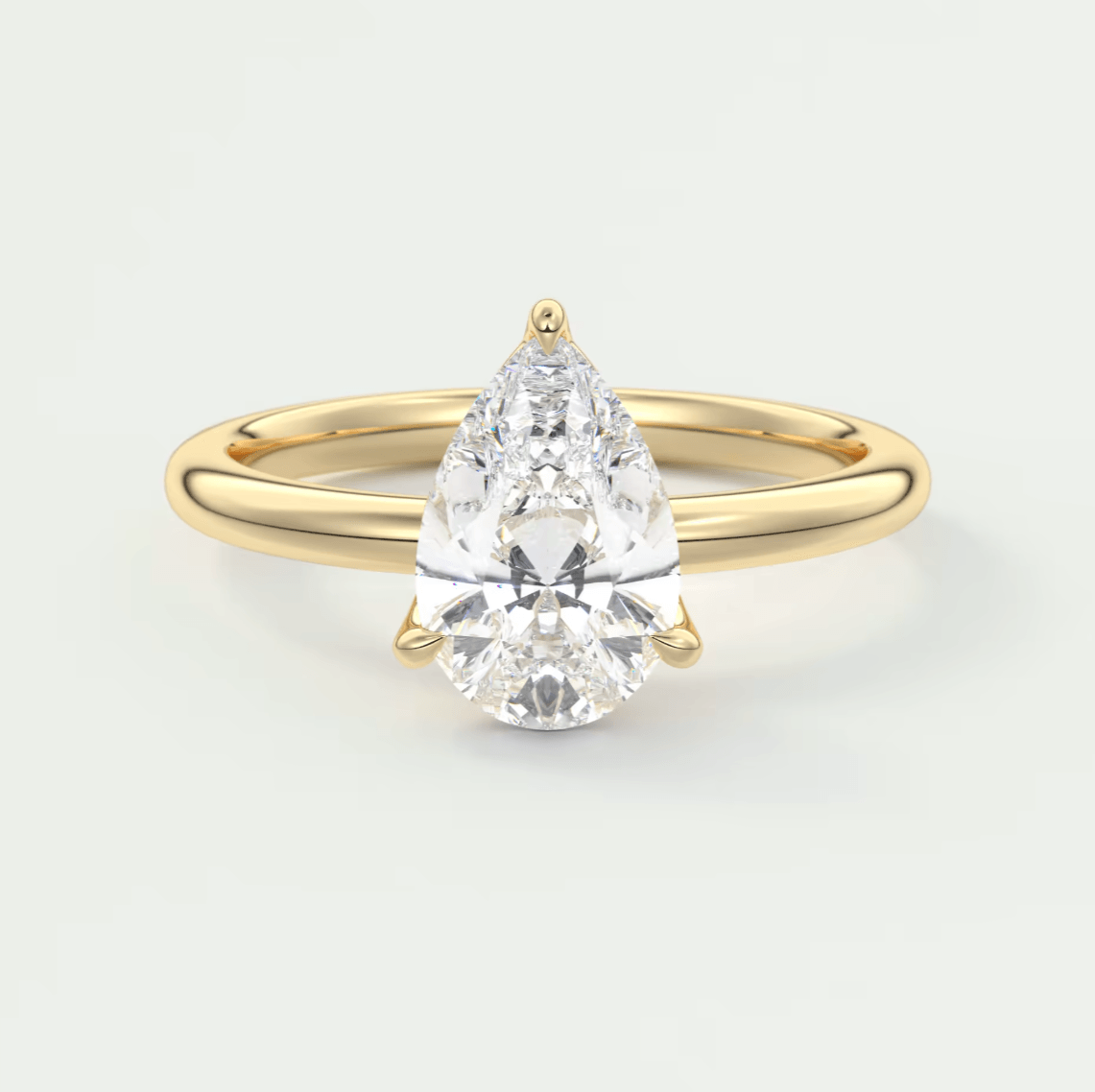 Pear-shaped diamond engagement ring with gold band and prong setting.