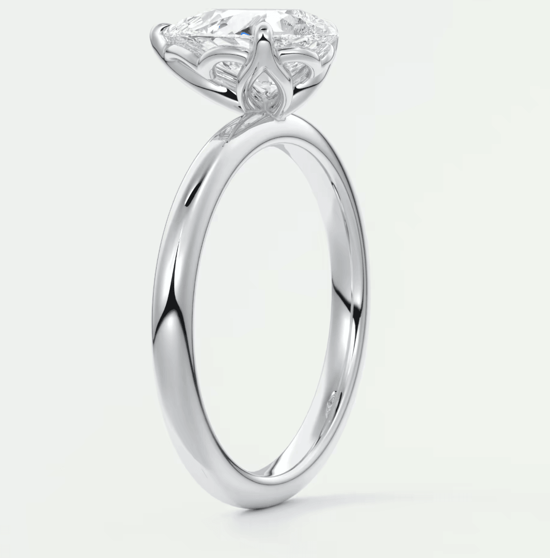 White gold engagement ring with a large, round diamond and intricate floral detailing on the band.