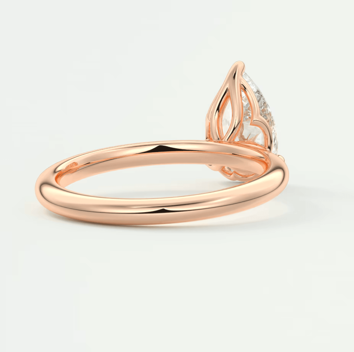 Rose gold engagement ring with a diamond center stone and intricate leaf design on the band.