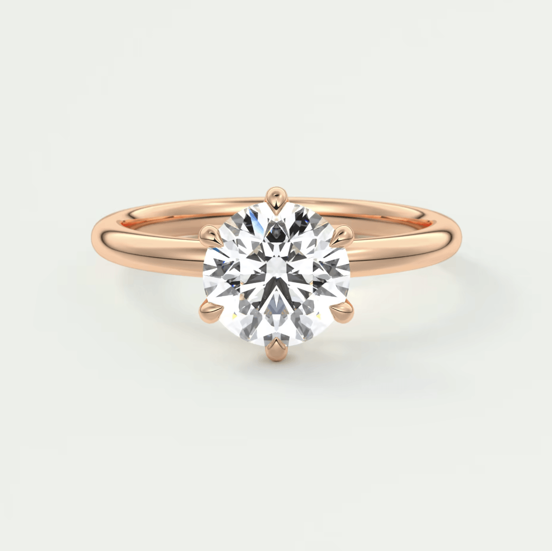 18-karat rose gold engagement ring with a round diamond center stone and four prongs.