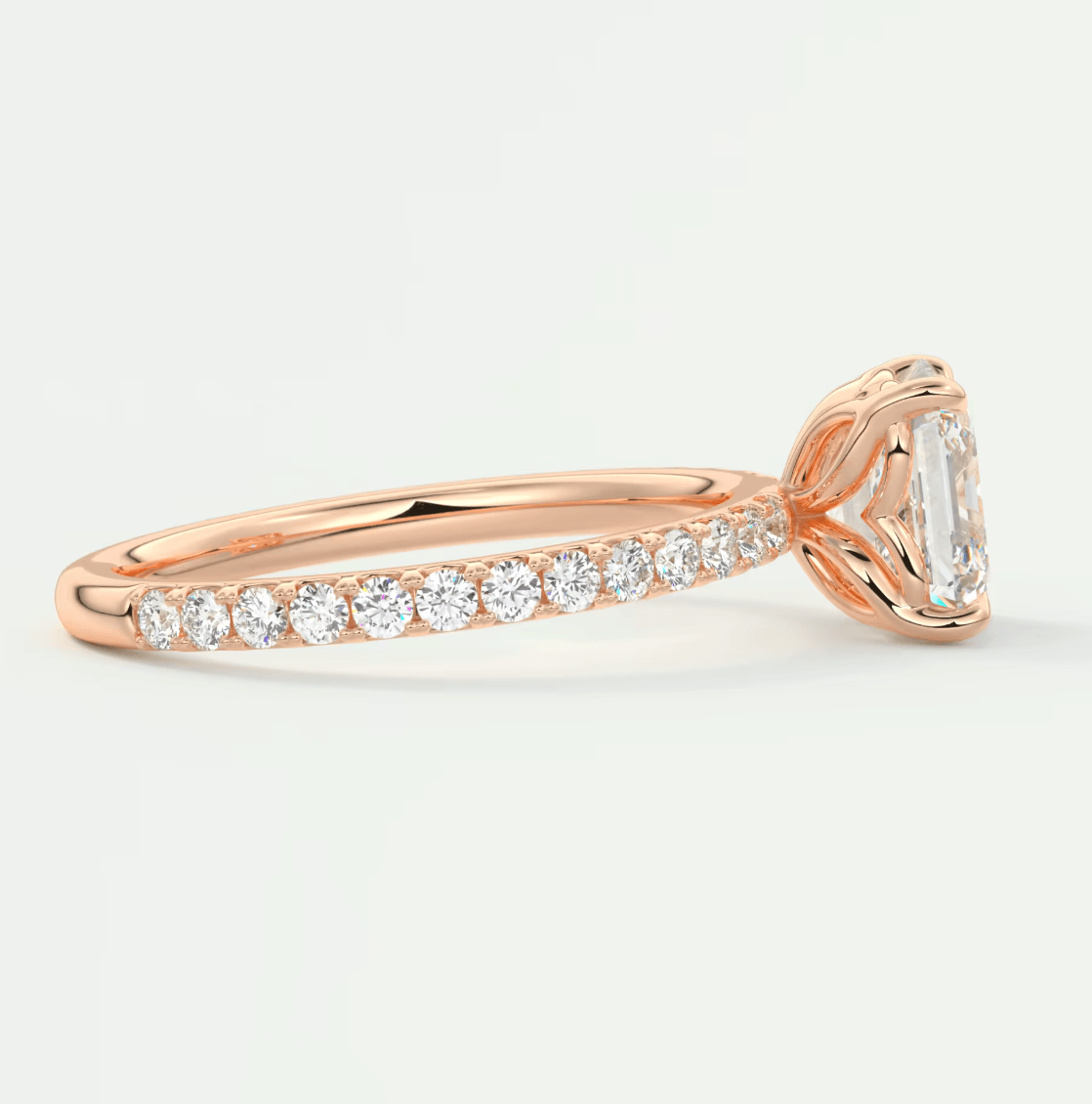 18k rose gold engagement ring with an emerald-cut diamond and channel-set diamonds on the band.