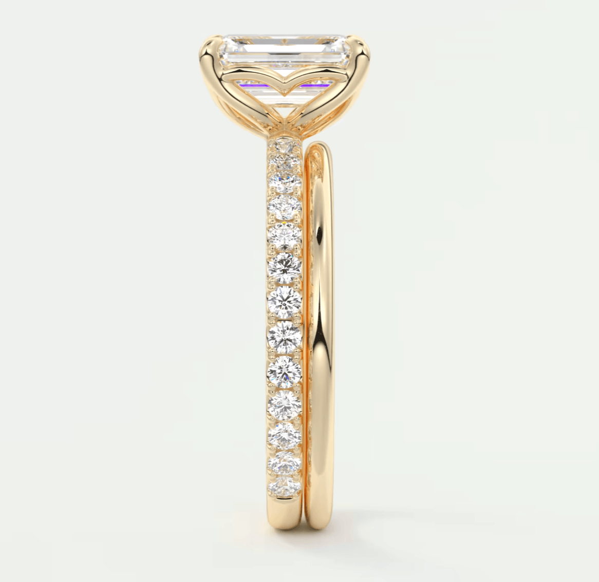 18k yellow gold engagement ring with an emerald-cut diamond and pavé set diamonds on the band.