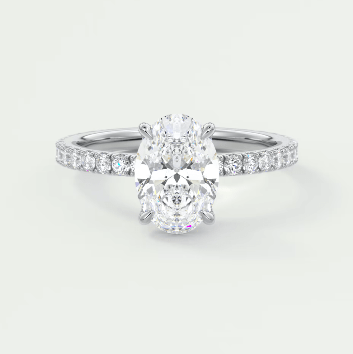 18k white gold engagement ring with an oval diamond center and pave set diamonds on the band.