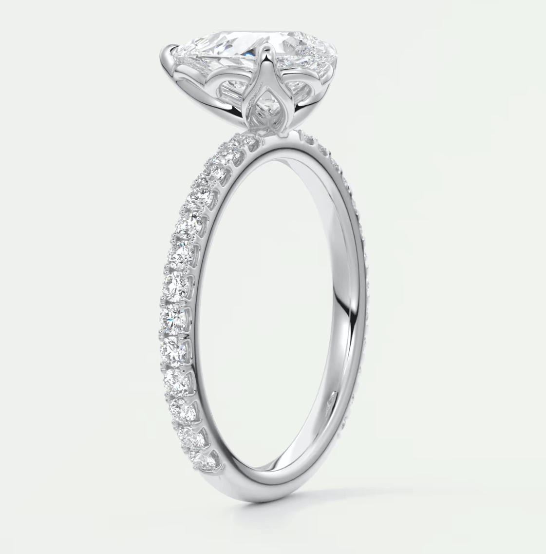 18-karat white gold engagement ring with a pear-shaped diamond and round diamonds on the band.