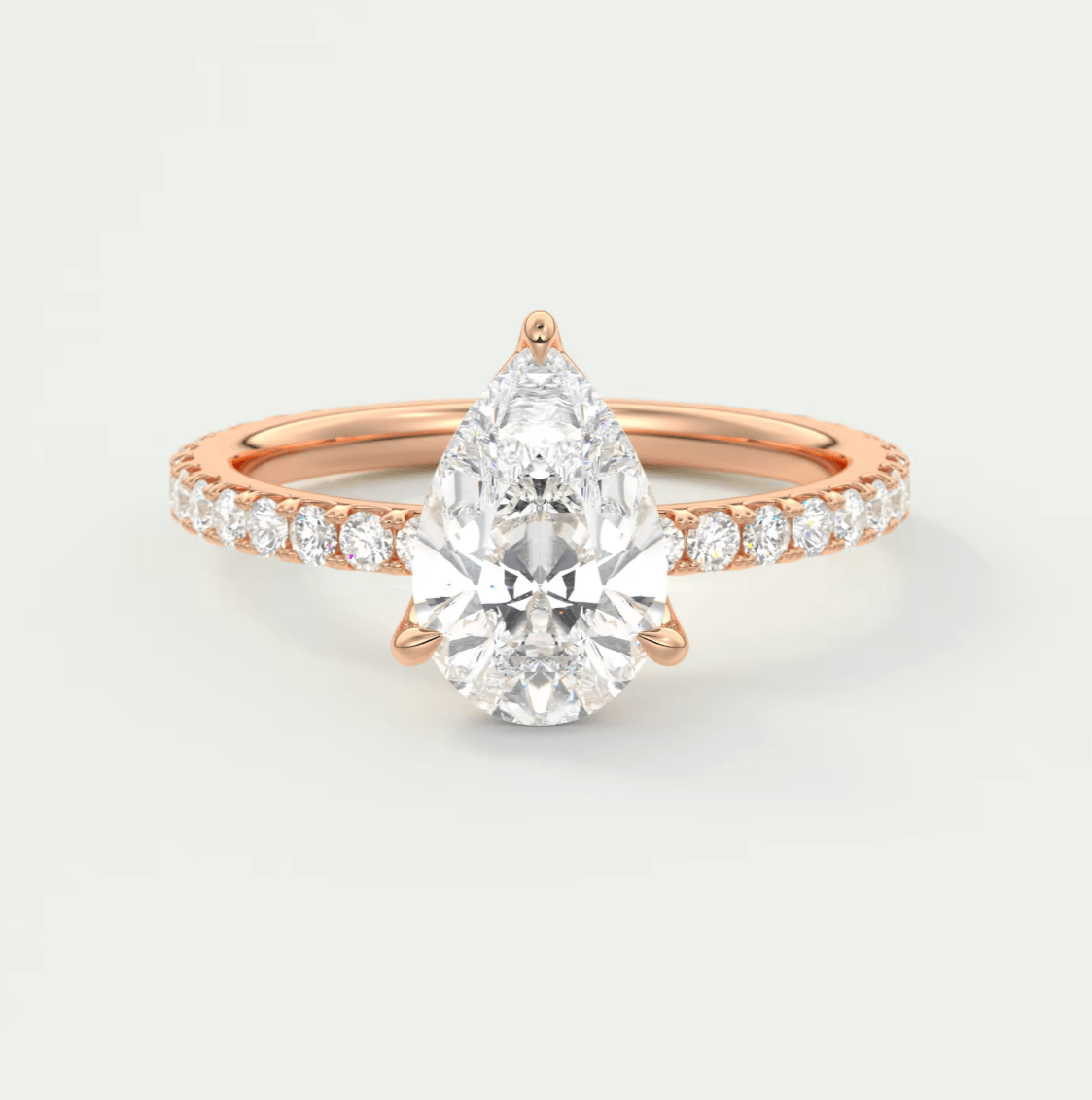 18k rose gold engagement ring with a pear-shaped diamond and small round diamonds on the band.