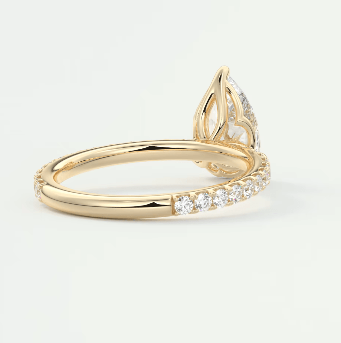 18k yellow gold engagement ring with a pear-shaped diamond and pave set diamonds on the band.