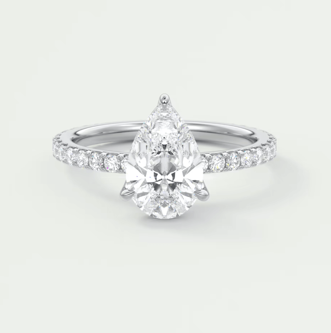 Pear-shaped diamond engagement ring with white gold band and pavé diamonds on the shoulders.