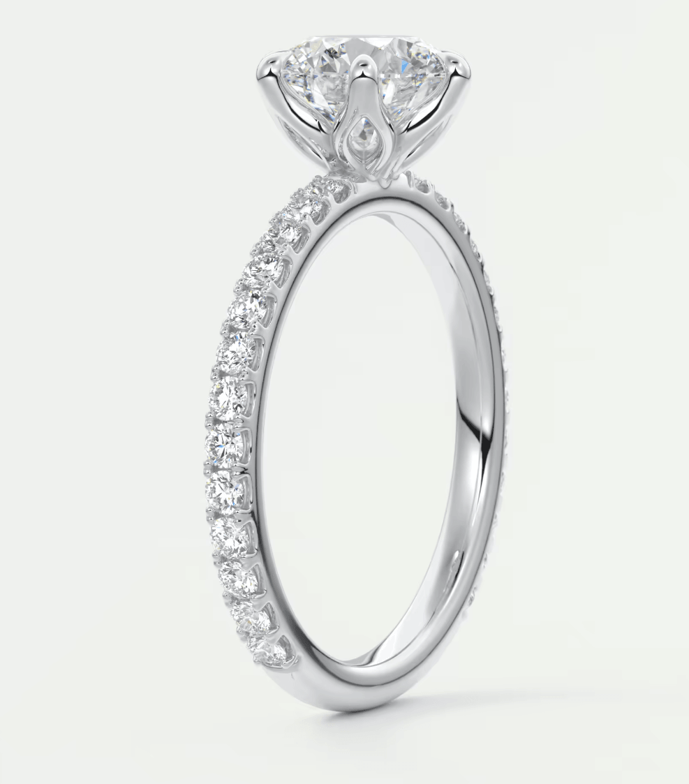 18-karat white gold engagement ring with a round diamond center and pavé set diamonds on the band.