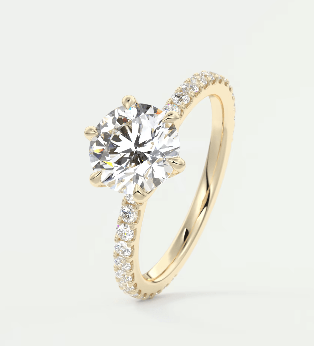 18-karat yellow gold engagement ring with a round diamond center and pave set diamonds on the band.