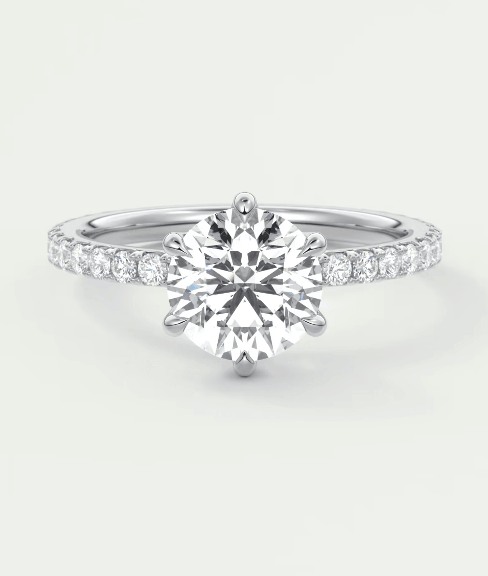 18-karat white gold engagement ring with a round diamond center and pavé set diamonds on the band.