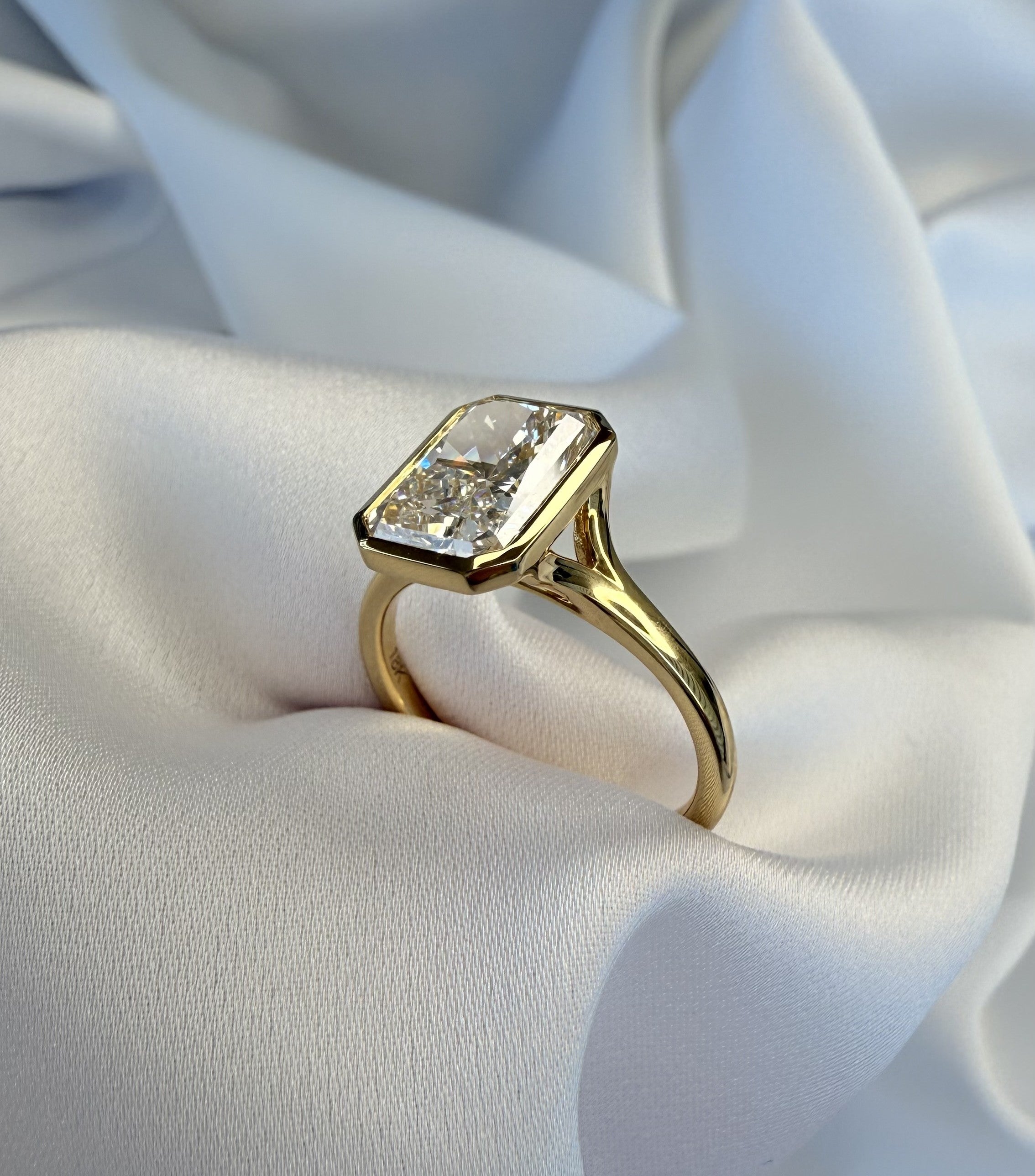 Gold ring with a large diamond on a white fabric background