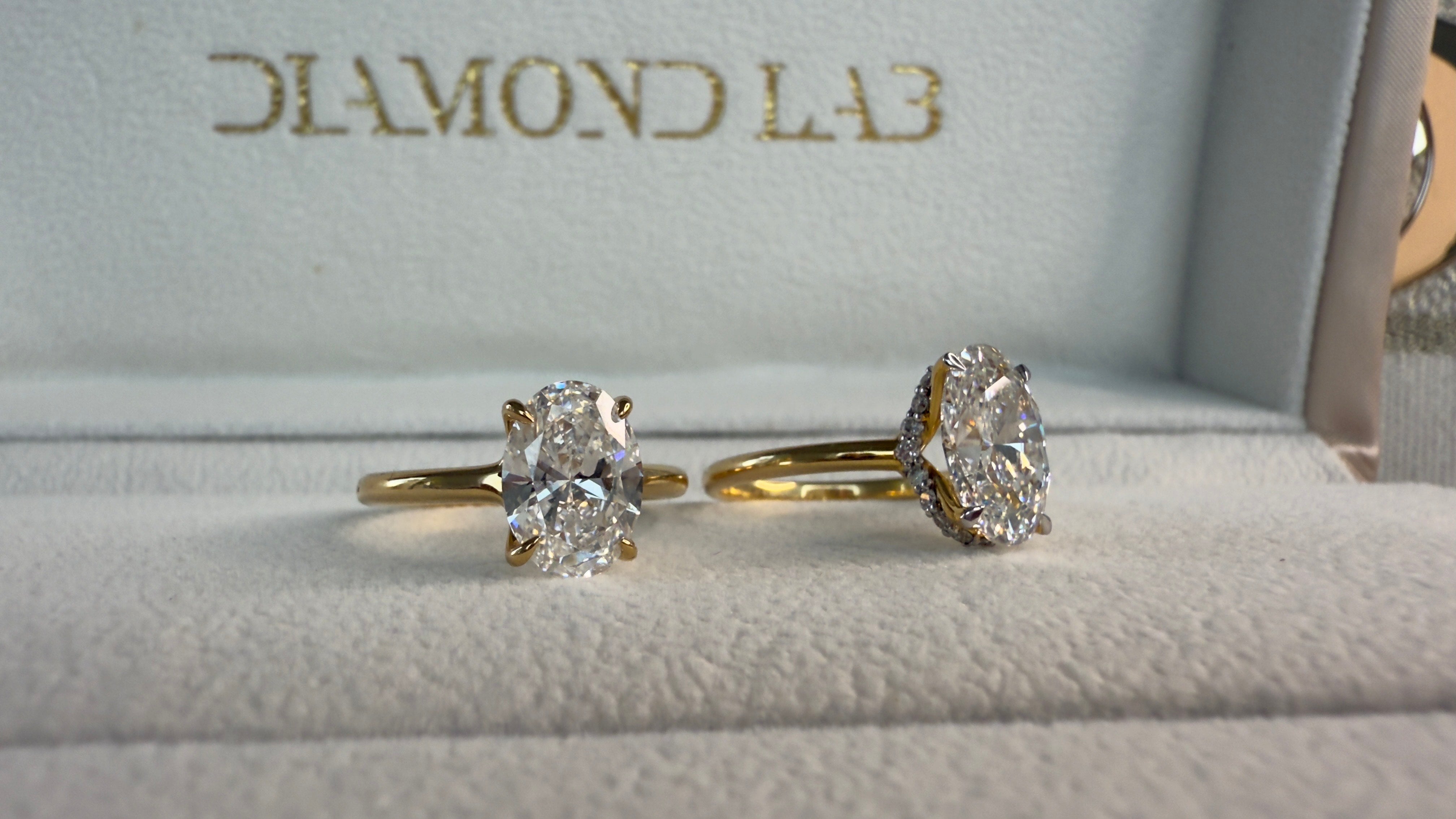 Two diamond rings on a cushioned surface with 'Diamond Lab' branding.