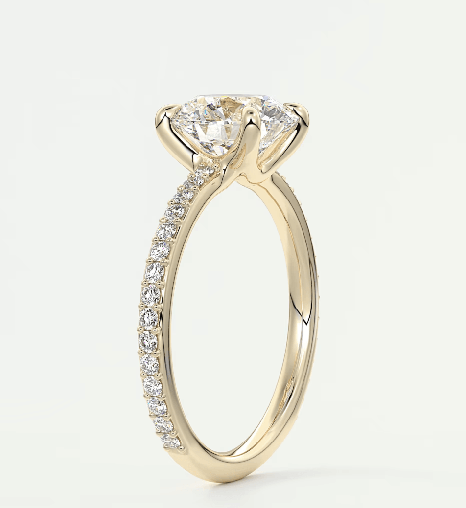 18-karat yellow gold engagement ring with a round diamond center and pave set diamonds on the band.