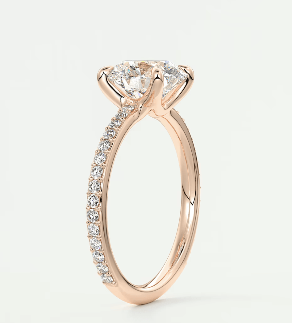 18-karat rose gold engagement ring with a round diamond center and pavé diamonds on the band.