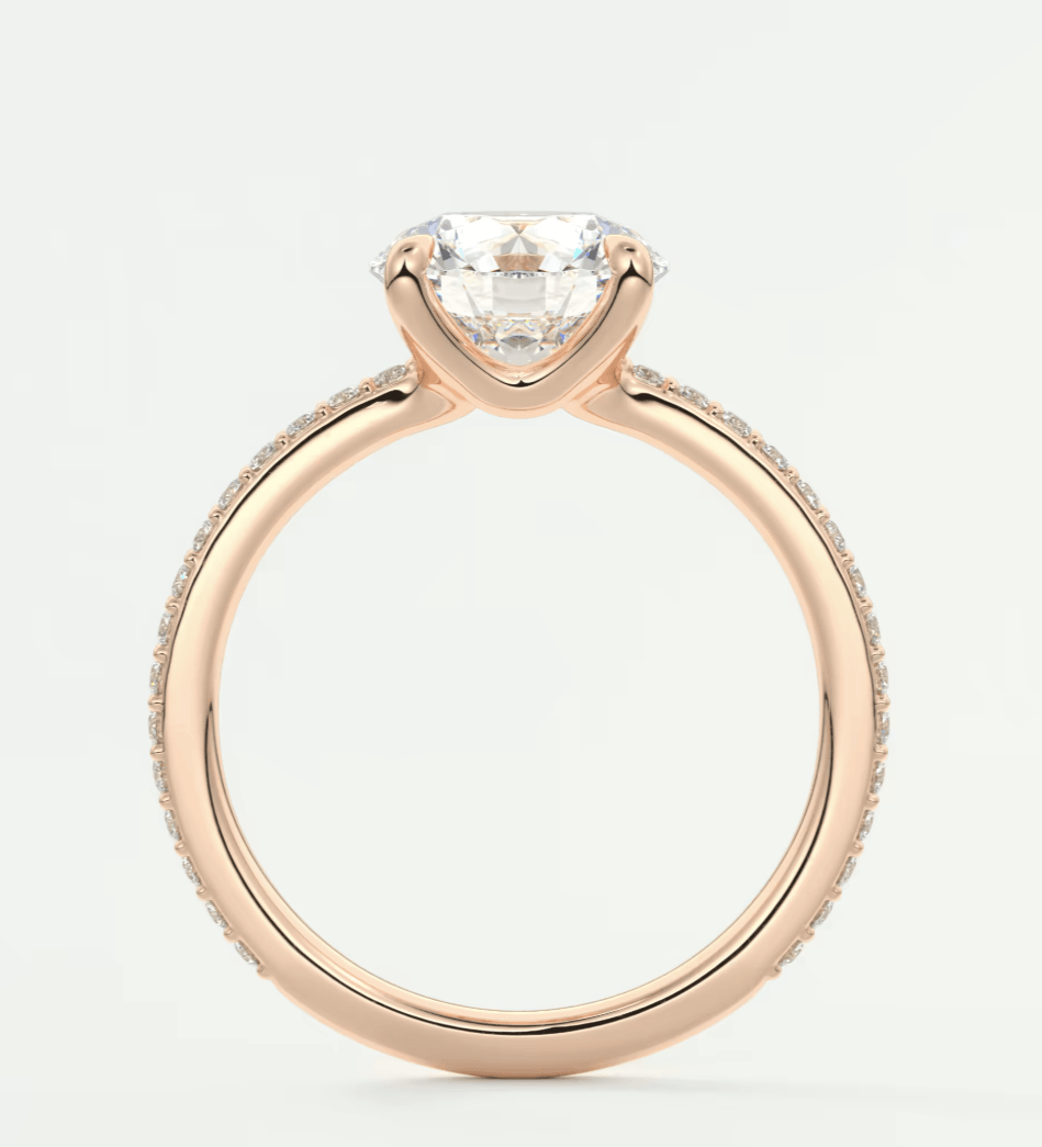 18-karat rose gold engagement ring with a round diamond center stone and pave set diamonds on the band.