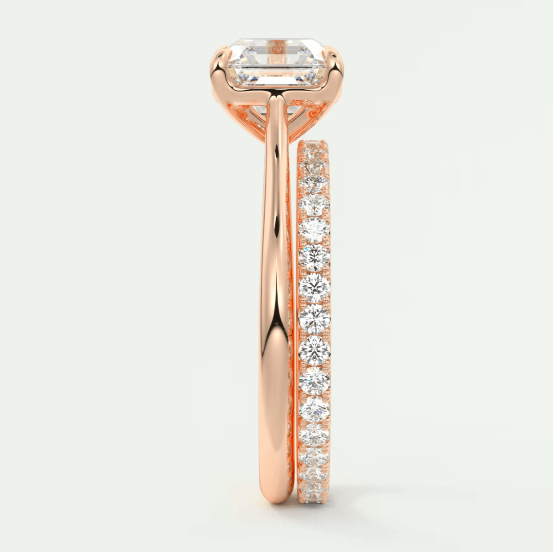 18-karat rose gold engagement ring with a baguette-cut diamond center stone and round diamonds on the band.