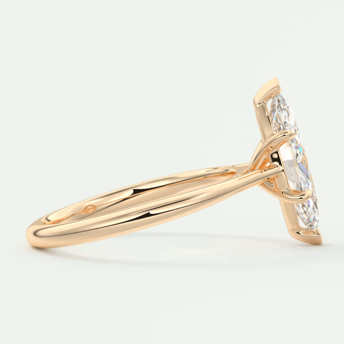 18k rose gold diamond engagement ring with a marquise-cut center stone and two smaller diamonds on either side.