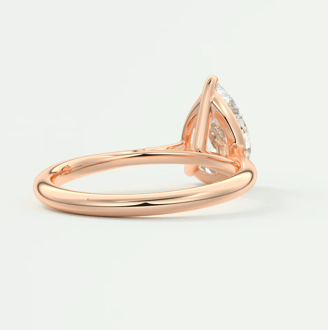 Rose gold diamond engagement ring with a pear-shaped stone and intricate band design.