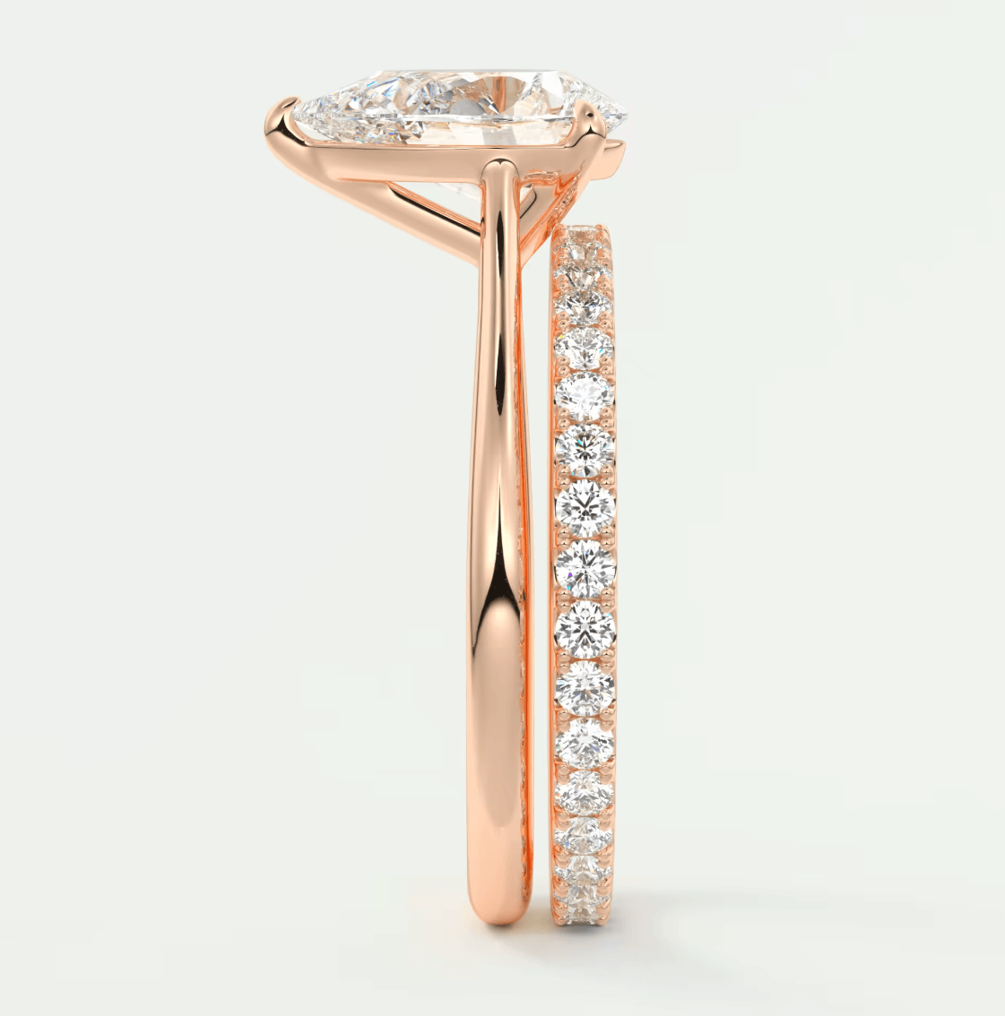 Rose gold diamond engagement ring with a pear-shaped center stone and side bands featuring round diamonds.