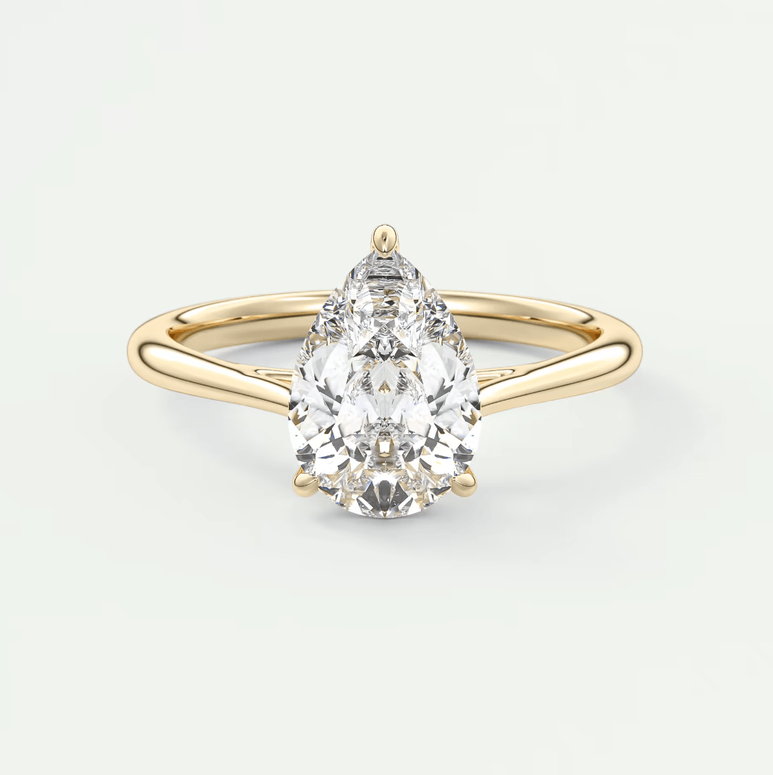 Pear-shaped diamond engagement ring with a yellow gold band and prong setting.