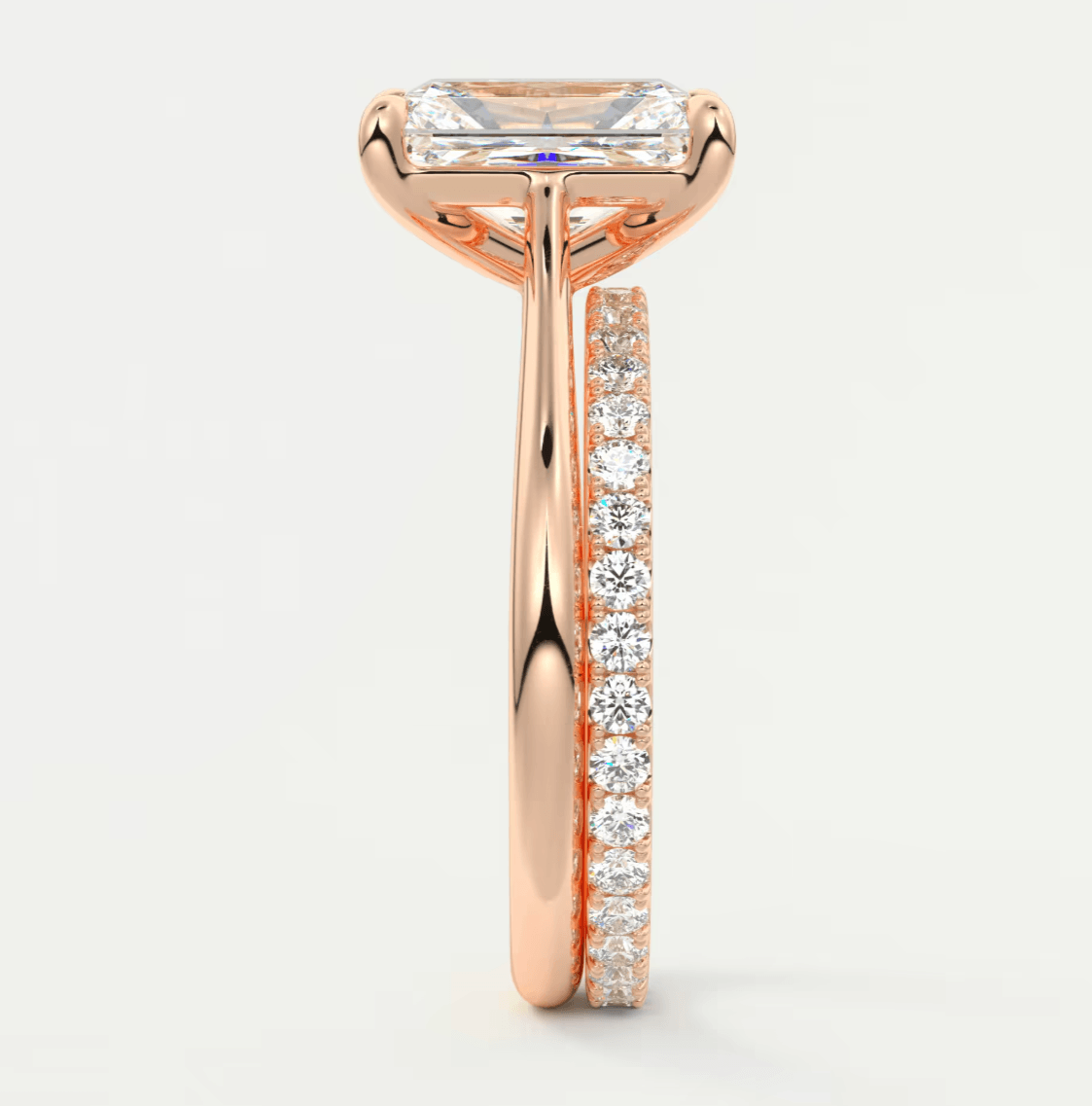18k rose gold engagement ring with emerald-cut diamond and pave set diamonds on the band.