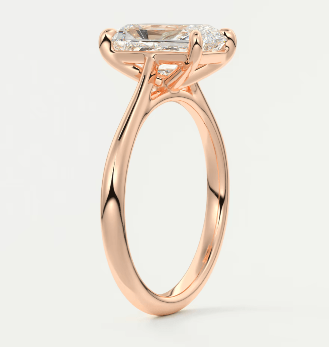 18k rose gold engagement ring with a marquise-cut diamond and two smaller diamonds on the band.