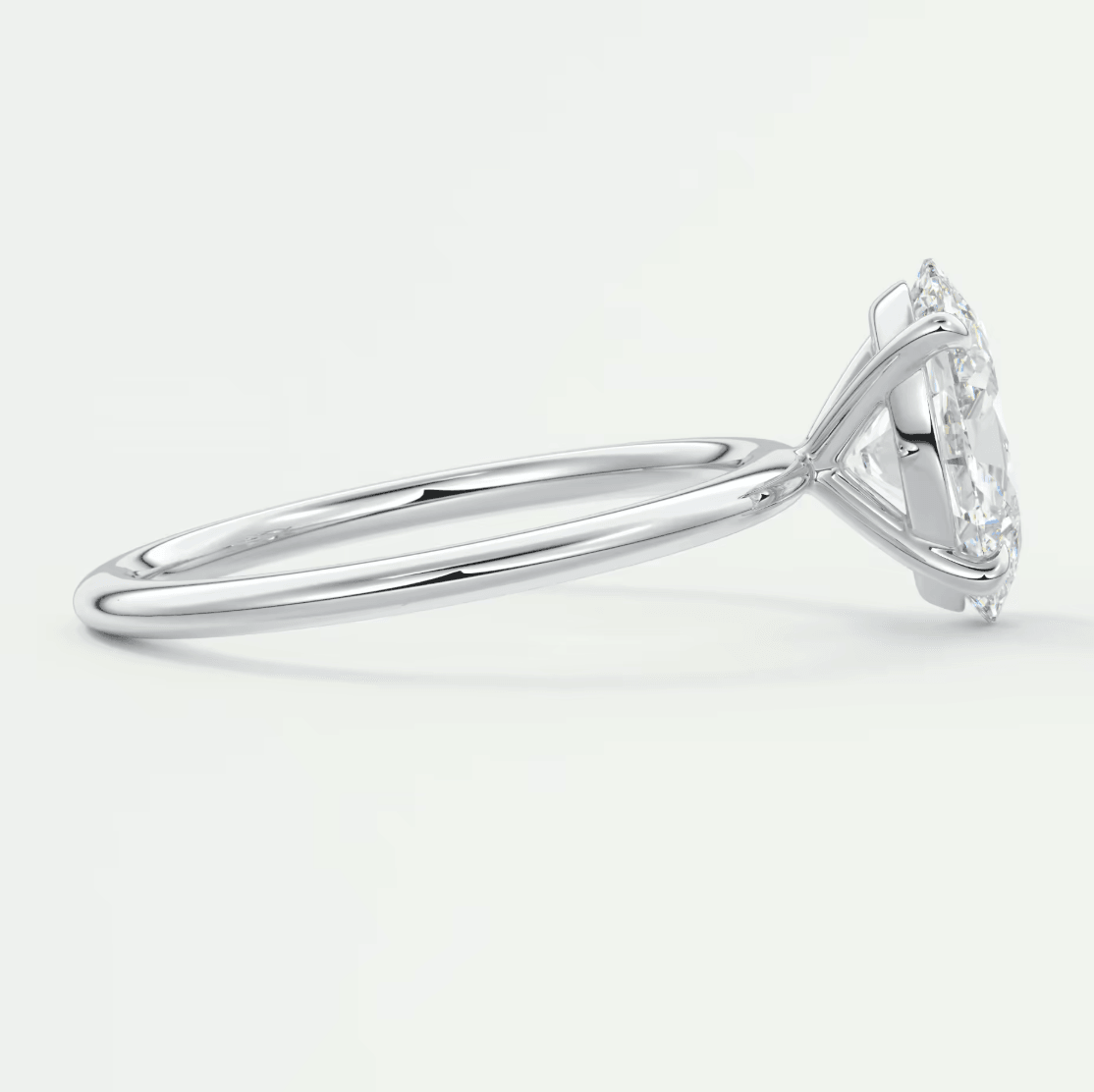 White gold marquise diamond engagement ring with three prongs and small diamonds on the band.