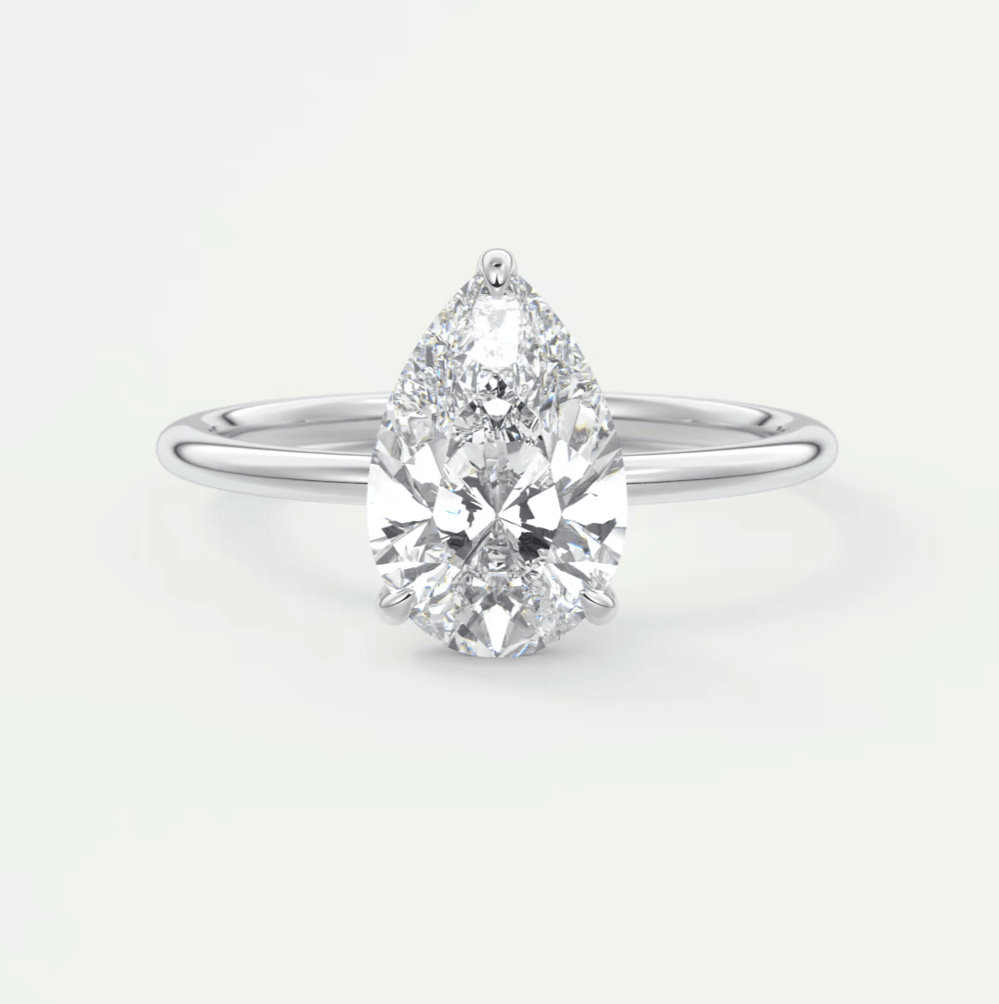 Pear-shaped diamond engagement ring with white gold band and halo of smaller diamonds.