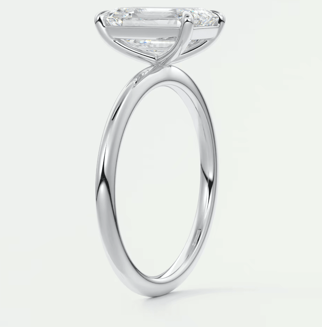 White gold emerald cut diamond engagement ring with a delicate band.