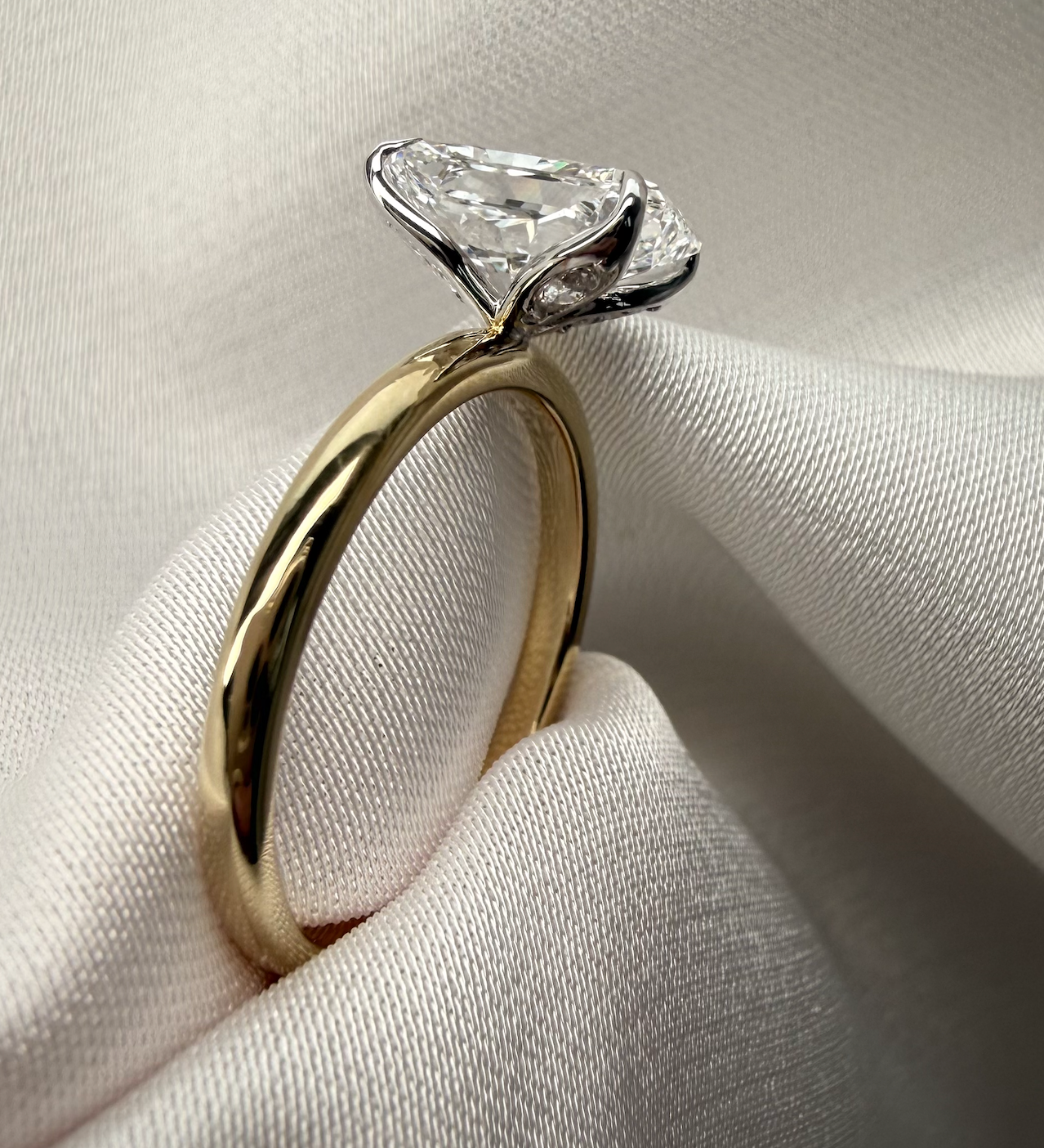 Gold ring with a diamond on a white fabric background