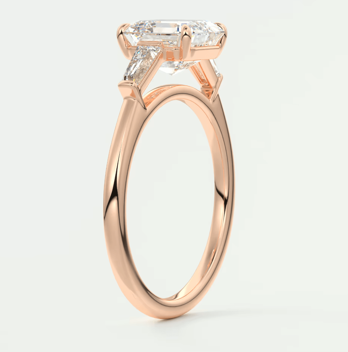 18k rose gold engagement ring with emerald-cut diamond and side trillons.