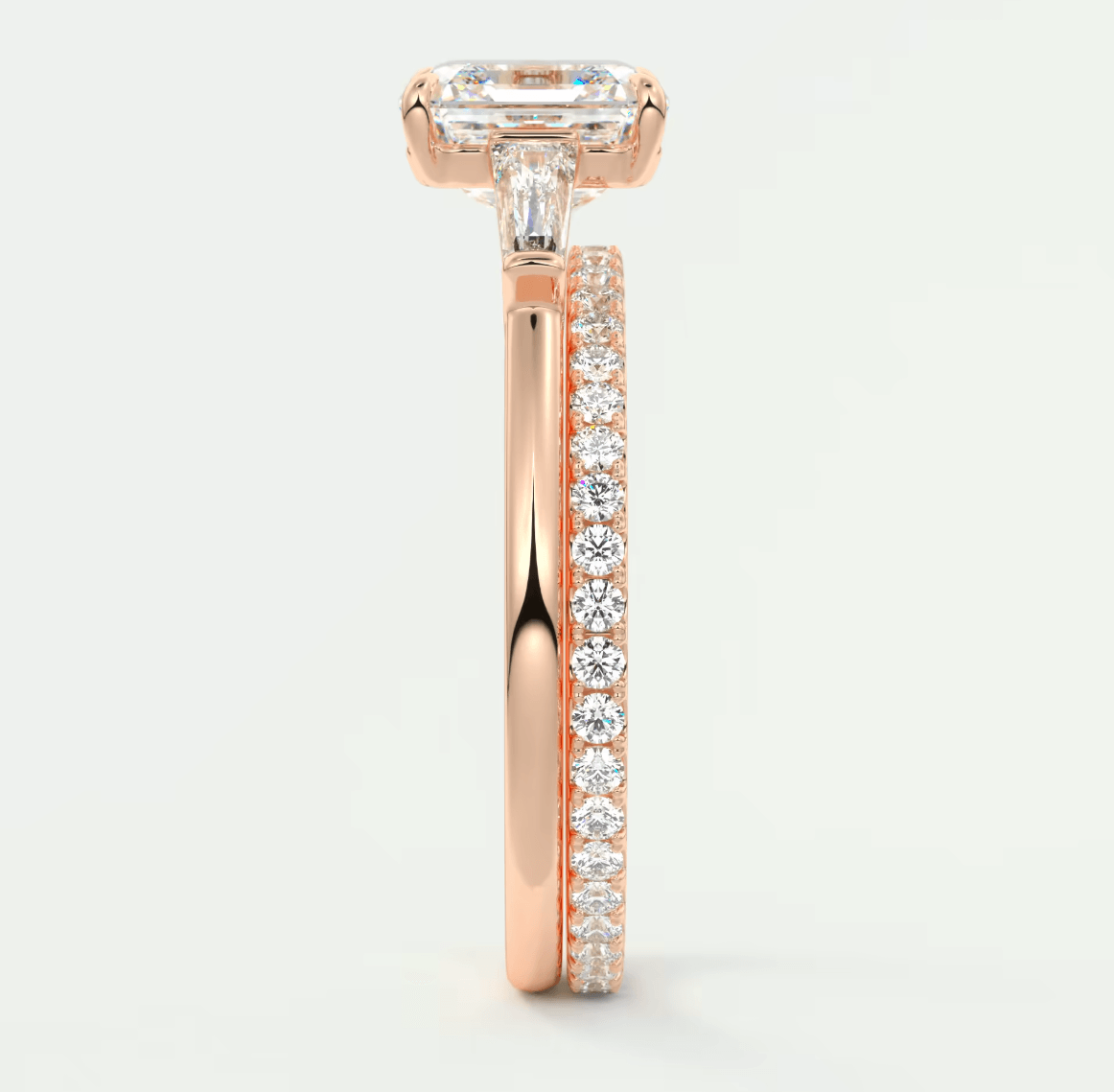 18k rose gold diamond engagement ring with an emerald cut center stone and a pave set band.
