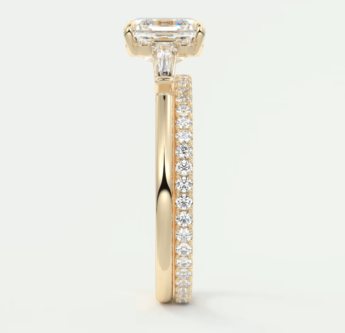 18k yellow gold engagement ring with an emerald-cut diamond center stone and pave set diamonds on the band.