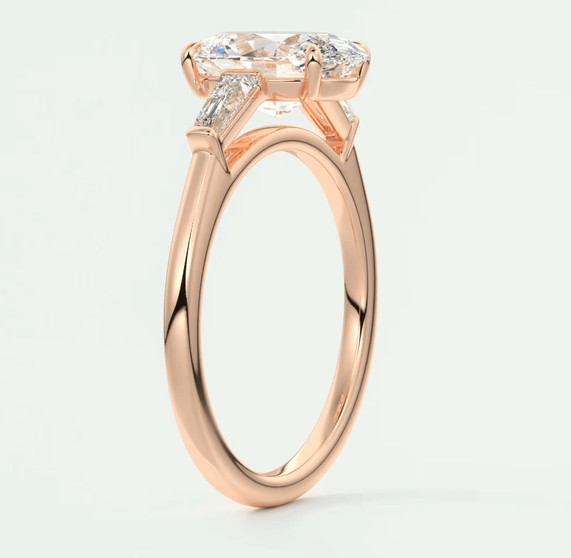 18k rose gold engagement ring with a marquise-cut diamond and two smaller diamonds on each side.